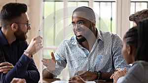 Smiling male african leader talking to colleagues at office briefing