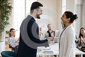 Smiling male boss handshake female colleague greeting with success