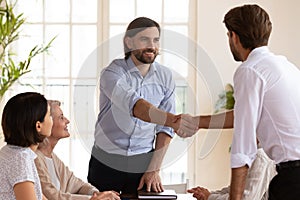 Smiling male boss shaking hands with young manager.