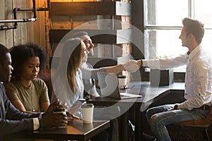 Smiling male broker greeting customers with handshake at cafe me