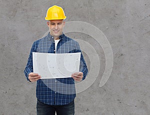 Smiling male builder in helmet with blueprint