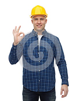 Smiling male builder in helmet showing ok sign