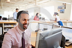 Smiling male call centre worker looking at screen, close-up