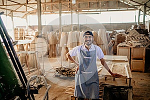 smiling male carpenter standing casually in a woodcraft warehouse