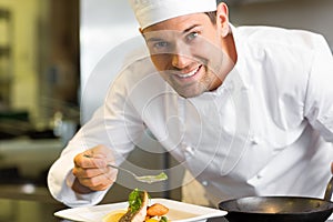 Smiling male chef garnishing food in kitchen