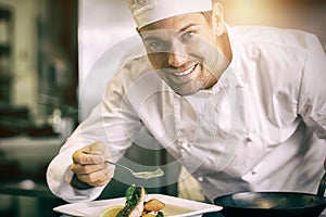 Smiling male chef garnishing food in kitchen