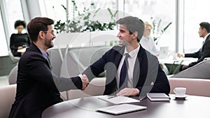 Smiling male colleagues shake hands getting acquainted at meeting photo