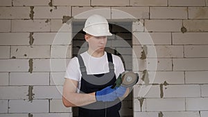 A smiling male construction worker in a white helmet with a working circular saw