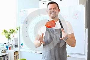 Smiling male cook catching flying red bell pepper