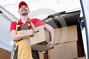 Smiling male courier holding large cardboard box