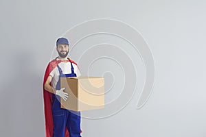 Smiling male courier in a work uniform wears a red superhero cloak and delivers goods quickly.