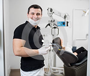 Smiling male dentist with ceramic braces holding dental tools