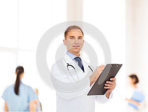 Smiling male doctor with clipboard and stethoscope