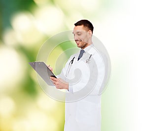 Smiling male doctor with clipboard and stethoscope