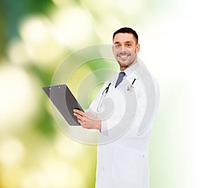 Smiling male doctor with clipboard and stethoscope