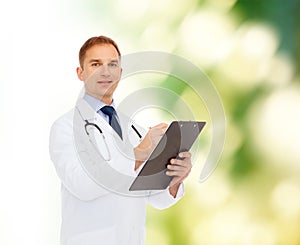 Smiling male doctor with clipboard and stethoscope