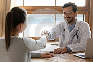 Smiling male doctor handshake female patient at meeting