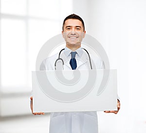 Smiling male doctor holding white blank board