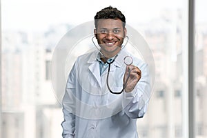 Smiling male doctor looking at camera and showing stethoscope.