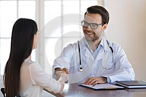 Smiling male doctor shake hand of female patient