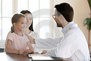 Smiling male doctor stroking small cute girl patient.