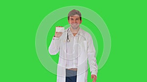 Smiling male doctor walking and advertising pills looking at camera on a Green Screen, Chroma Key.