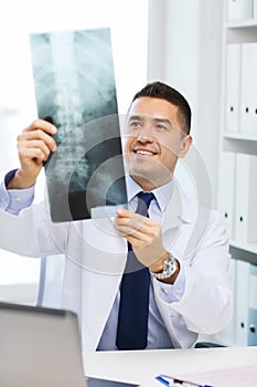 Smiling male doctor in white coat looking at x-ray