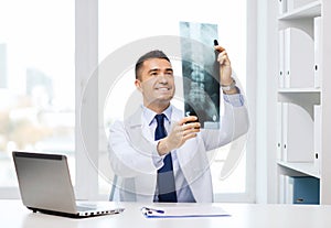 Smiling male doctor in white coat looking at x-ray