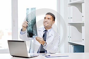 Smiling male doctor in white coat looking at x-ray