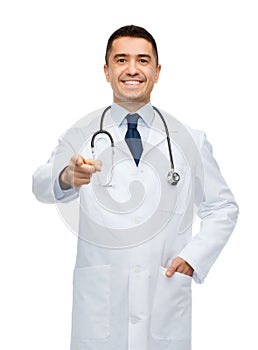 Smiling male doctor in white coat pointing at you