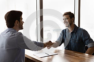 Smiling male employee handshake closing deal at meeting