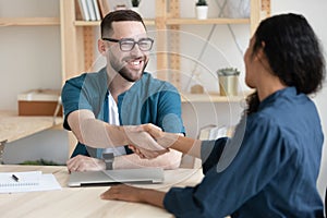 Smiling male employer handshake female job candidate at meeting