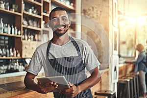 Smiling male entrepreneur in his coffee shop holding digital tab