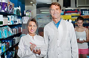 Smiling male and female pharmacists wearing white coats working