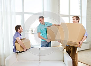Smiling male friends carrying boxes at new place