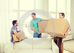 Smiling male friends carrying boxes at new place