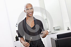 Smiling male hairdresser holding scissor and hairbrush photo