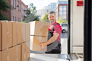 Smiling Male Mover Loading The Cardboard Boxes In Van