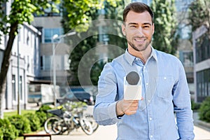 smiling male news reporter taking interview with microphone photo