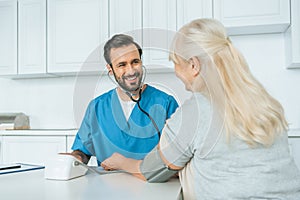 smiling male nurse measuring blood pressure to