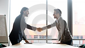 Smiling male partners handshake greeting at meeting