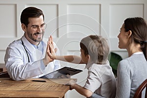Smiling male pediatrician giving high five to little patient
