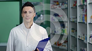 Smiling male pharmacist in white coat at drugstore
