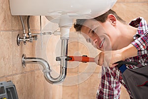 Plumber Fixing Sink Pipe With Adjustable Wrench