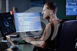 Smiling Male IT Programmer Using Computer Working at Desk Indoors