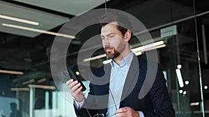 Smiling male reading pleasant information in social medias on phone in office