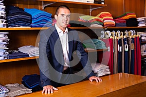 Smiling male seller demonstrating shirts to customer in men cloths store