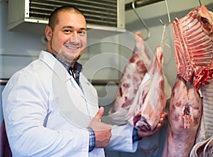 Smiling male shop staff cutting sirloin at top