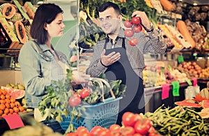 Smiling male shopping assistant helping customer to buy fruit an