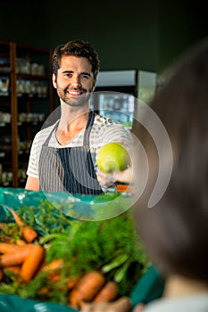 Smiling male staff assisting a woman with grocery shopping